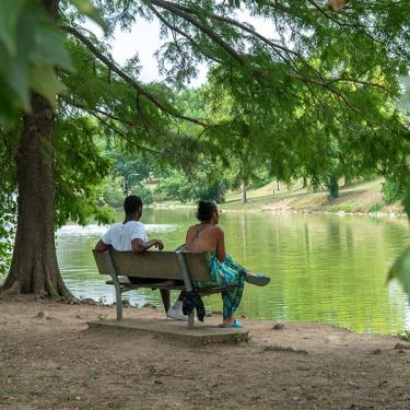 couple sitting on park bench looking at river