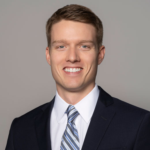 Photo of Jacob Robertson wearing black sportcoat, white shirt, and blue striped tie.
