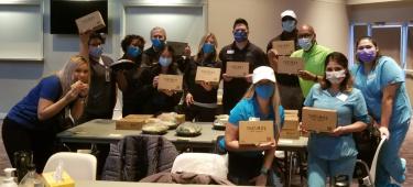 Photo of a group of medical staff holding Thelma's Kitchen boxed lunches.