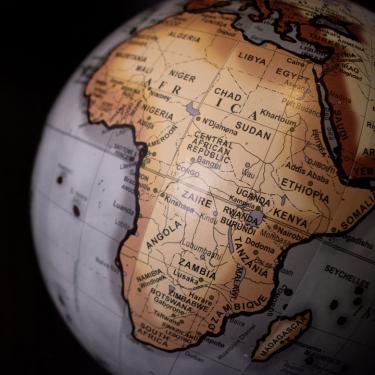 Photo of Globe in grayscale with Africa highlighted in gold-tones.