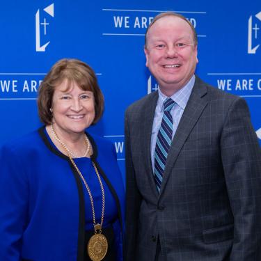 Photo of Dr. Sandra Cassady, Ph.D. wearing blue jacket with black trim and gold medallion next to Joe Reardon, wearing windowpane sportcoat and with dark and light blue striped tie.