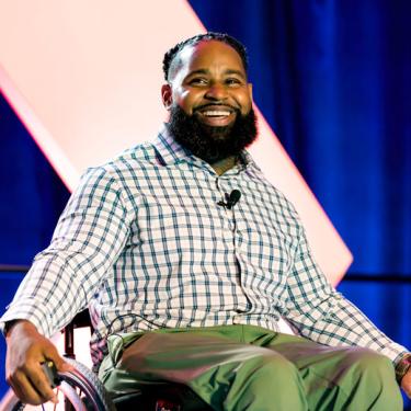 2022 Small Business Celebration keynote speaker, Wesley Hamilton, Mental & Physical Health Advocate for Overcoming Adversity; Executive Director of Disabled But Not Really (DBNR), wearing green check shirt, green pants, sitting in wheel chair.