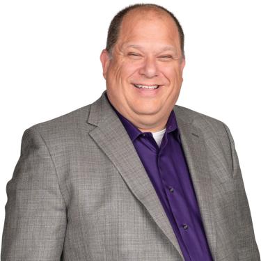 Photo of Dave Haake in gray suit jacket and purple shirt