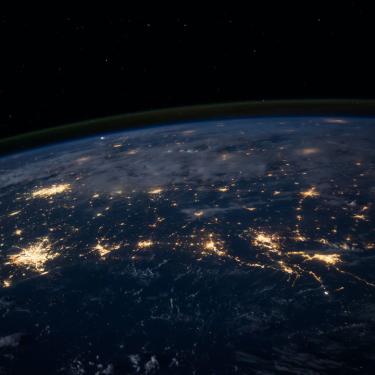 Photo of earth from space showing city lights on the surface and the Kármán line.