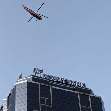 Photo of helicopter lowering the letters Ac onto the top of Academy Bank's downtown KC building.