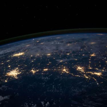 Photo of earth at night from space, showing lights of large cities.